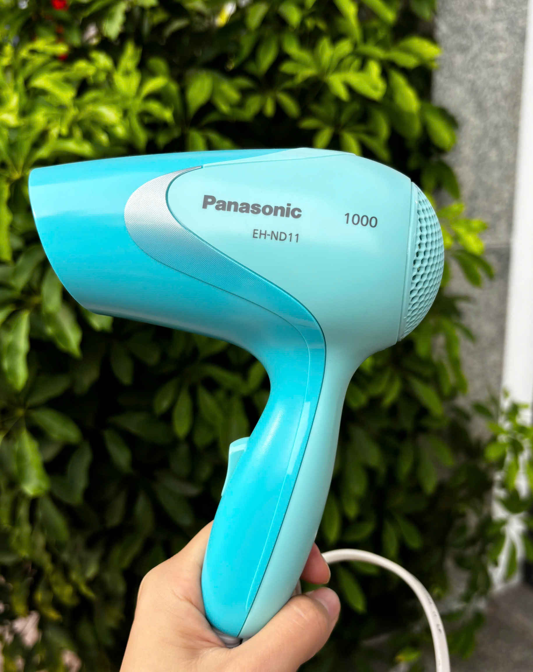 Máy sấy tóc Panasonic EH-ND11 màu xanh ngọc, công suất 1000W, được cầm trên tay